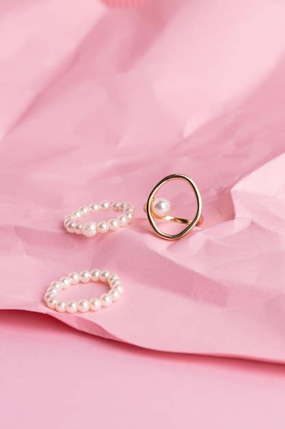 Premium Photo | Golden jewelry on a pink background stylish gold ring with pearl on pink ...