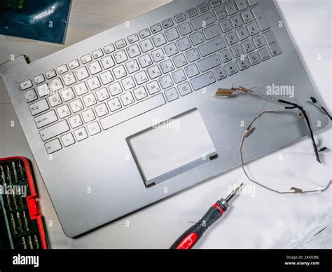 Repair and maintenance of computer laptop, laptop lid disassembled and screwdriver hanging above ...