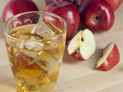 A Glass of Fresh Cold Apple Juice with Ice beside Apples on a Wooden ...