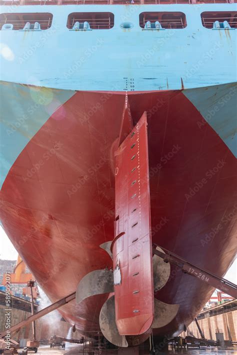 Back view on the container ship. Ship is inside a dry dock for routine maintenance and painting ...