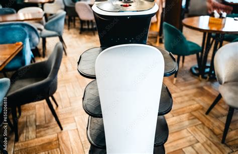 Robot waiter serve food at modern restaurant table.Offering innovation futuristic high-tech ...