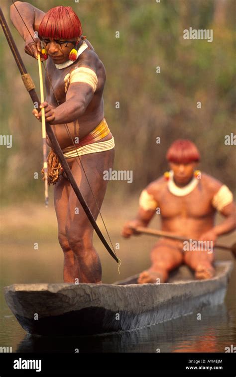 Xingu Amazon rainforest Brazil Yaulapiti indigenous People Indians in canoe fishing with bow and ...