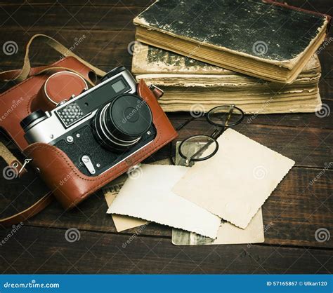 Retro Still Camera And Some Old Photos On Wooden Table Background | CartoonDealer.com #57165867