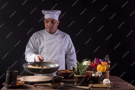 Premium Photo | Male chef in white uniform holding a frying pan sauteing spaghetti with fresh ...