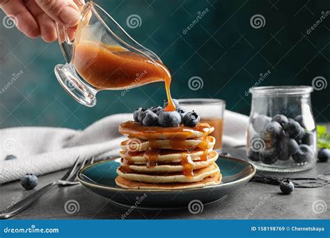 Woman Pouring Caramel Syrup Onto Fresh Pancakes with Blueberries at Grey Table Stock Image ...