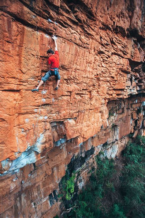 Fit rock climber climbing an extreme cliff face in a mountain by Micky ...