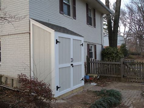 a white house with a black door and window on the side of it, in front of a fence