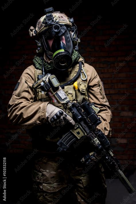 Soldier in gas mask with rifle in hands/Soldier in uniform and respirator standing on dark ...