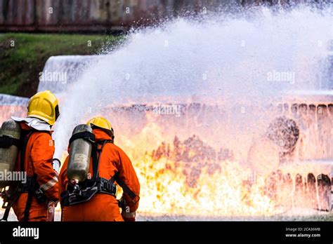 Firefighter using Chemical foam fire extinguisher to fighting with the fire flame from oil ...