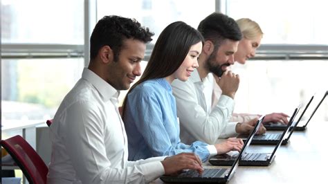 Smiling people working together in office. Team of programmers working in a team, huge windows ...