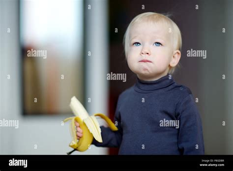 Funny toddler girl eating a banana Stock Photo - Alamy