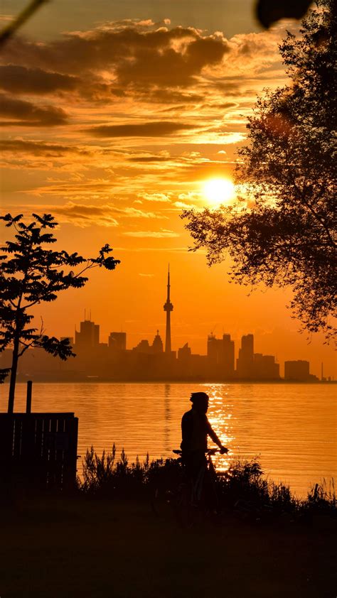 Download wallpaper 2160x3840 silhouette, city, buildings, sunset, sea ...