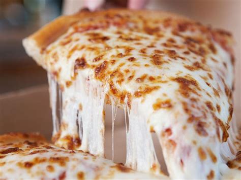 a slice of cheese pizza is being lifted from the box by a spatula with melted cheese on it