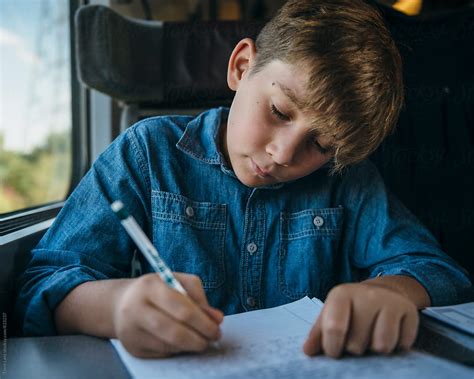 "Young Boy Writing A Letter While Travelling In Train" by Stocksy Contributor "Trent Lanz" - Stocksy