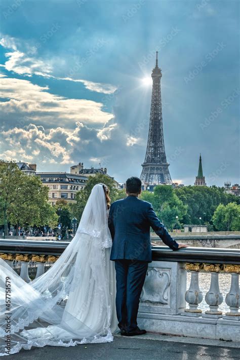 Un couple de jeunes mariés sur le pont Alexandre III à Paris face à la ...