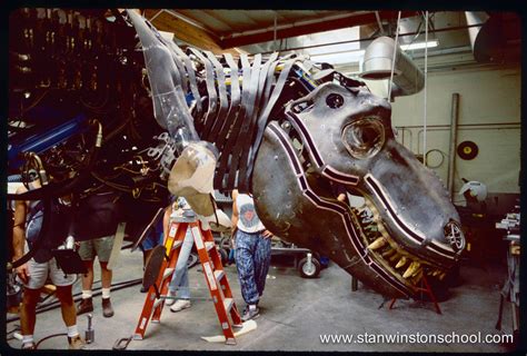 people are working on an elephant sculpture in a garage with other workers around the horse