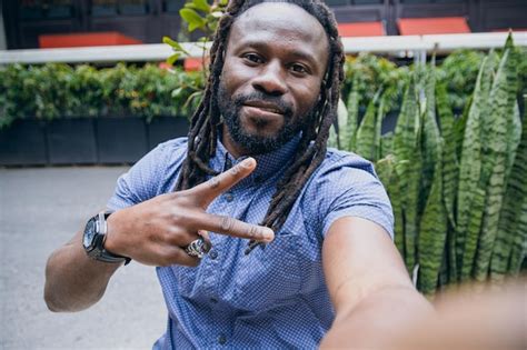 Premium Photo | Selfie portrait with phone of black man with dreadlocks and beard sitting ...