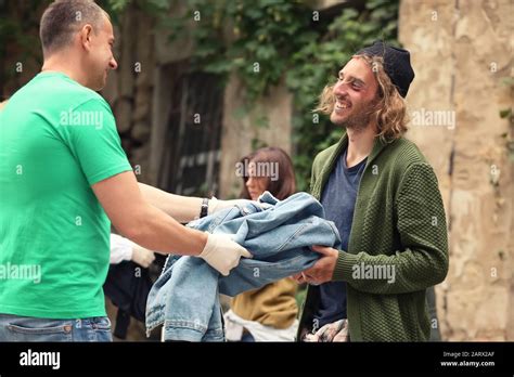 Volunteers giving clothes to homeless people outdoors Stock Photo - Alamy