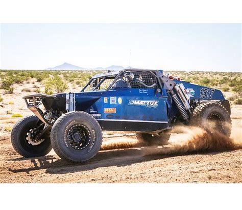 a blue truck driving through the desert with dirt on it's tires and wheels