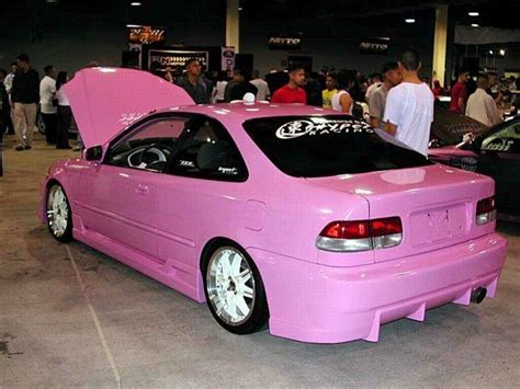 a pink car with its hood open in a showroom filled with people and ...