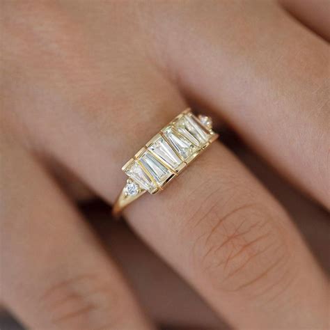 a woman's hand wearing a gold ring with three baguettes