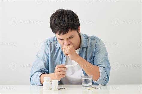 Sick young man looks at a thermometer 12745371 Stock Photo at Vecteezy