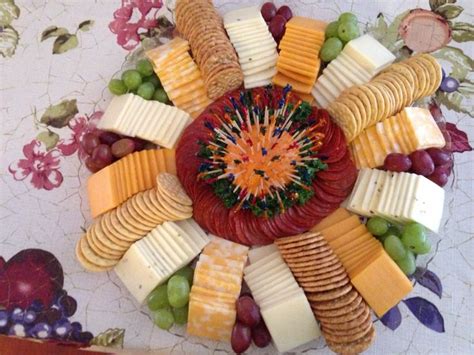 a platter filled with cheese, crackers and grapes