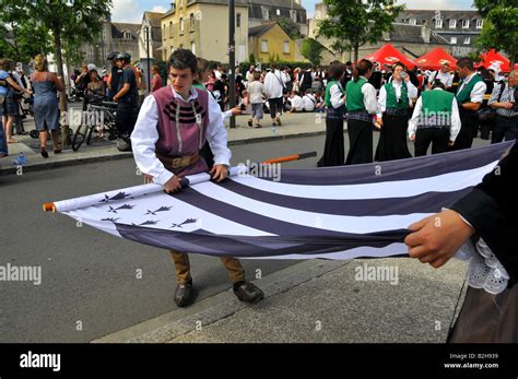 a couple of breton dancers are rolling up a breton flag during the Cornwall Festival in Quimper ...