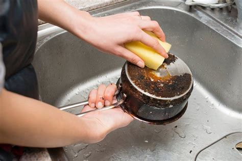 a person is using a sponge to clean a metal sink with an orange peel in it