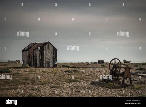 A rusted old piece of machinery near to an old abandoned hut on the shingle beach at Dungeness ...