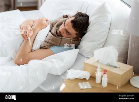 sick man measuring temperature by thermometer Stock Photo - Alamy