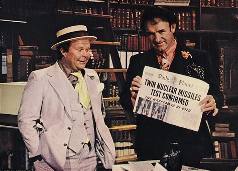 two men standing next to each other in front of a bookshelf holding a ...