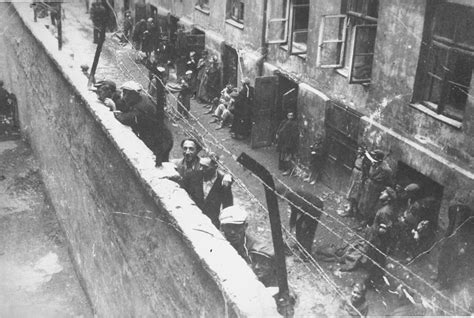 Jewish youth peer over the wall overlooking Mirowski Plac (Square) that divided the Warsaw ...