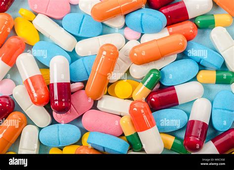 Colorful tablets and capsules pills medicine heap on blue background ...