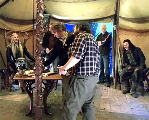 a group of men standing around a wooden table in a tent with people looking at it