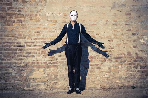 Mystery man with white mask against brick wall. 11401034 Stock Photo at Vecteezy