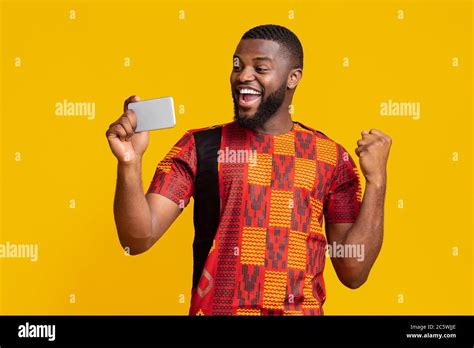 Happy black man holding phone and expressing happiness Stock Photo - Alamy