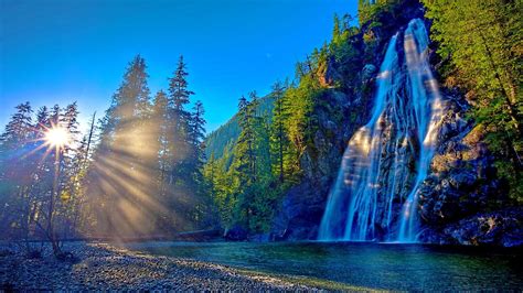 Waterfalls From Rock Pouring On Lake Between Green Trees Covered Mountains Under Blue Sky HD ...