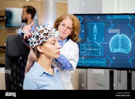 Doctor arranging neurology scanning headset for tests on a female patient. Scanning machine ...