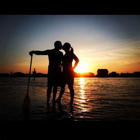 two people standing in the water at sunset