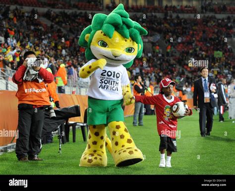 Zakumi, the official World Cup mascot walks hand in hand with a small girl on the pitch prior to ...