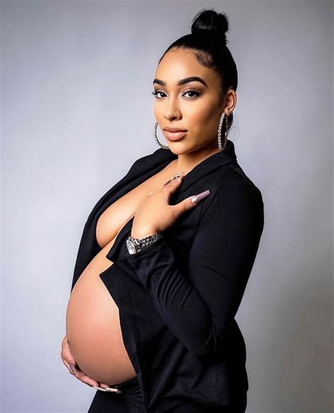 a pregnant woman posing for the camera with her hand on her belly and ...