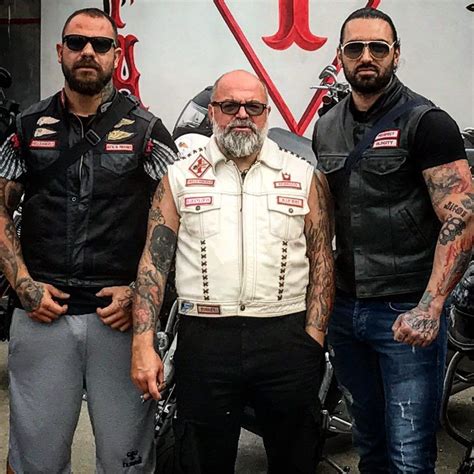 three men standing next to each other with tattoos on their arms and shoulders, wearing leather ...