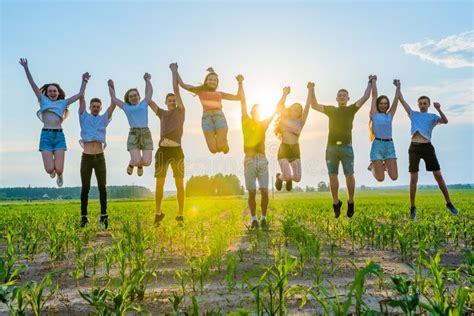 Friends are Jumping Holding Hands at Sunset. Stock Photo - Image of ...