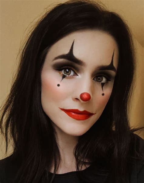 a woman with black hair and red nose makeup is wearing a clown make - up