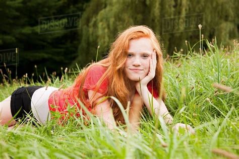 Teenage girl lying down on the grass chilling out - Stock Photo - Dissolve