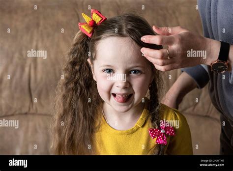 The mother combs the daughte hair and braid. The child jokingly shows his tongue. Positive ...