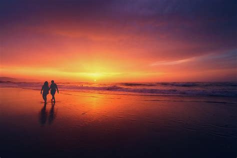 Couple Walking On Beach At Sunset Photograph by Mikel Martinez de Osaba - Pixels