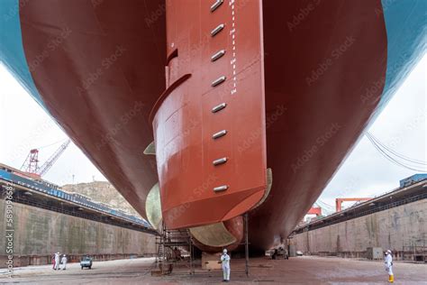 Aft view on the container ship inside dry dock, propeller on the first plan. Ship is inside a ...