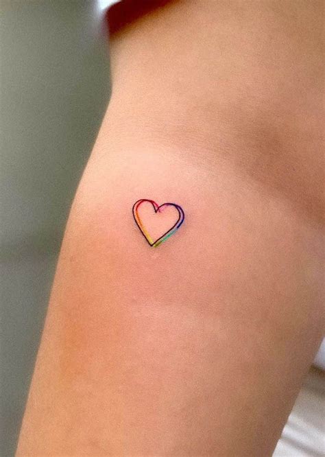 a small heart tattoo on the back of a woman's thigh, with rainbow colors